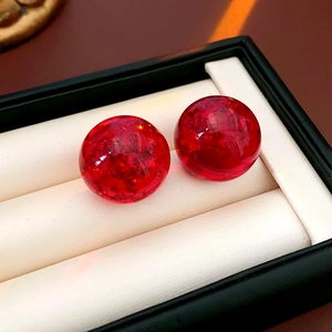Close-up of translucent red resin round earrings with gold foil details in a jewelry box