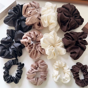 Detail view of satin scrunchies in various sizes and neutral colors like beige and brown