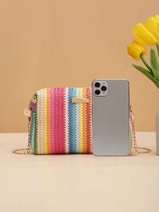 Detailed shot of a colorful striped straw bag with a gold chain strap and metal hardware