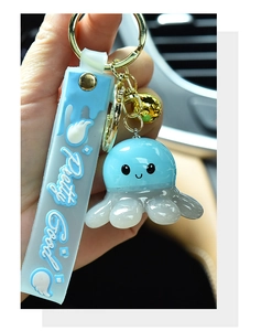 Close-up of cute light blue glowing resin octopus keychain with 'Pretty Good' strap