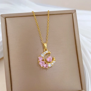 Macro view of gold titanium necklace with pink heart zircon and moon pendant in gift box