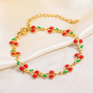 Detailed macro view of 18k gold plated cherry charm bracelet with red enamel and lobster clasp
