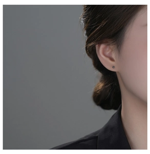 Close-up of minimalist black clover stud earring in S999 silver worn by a model