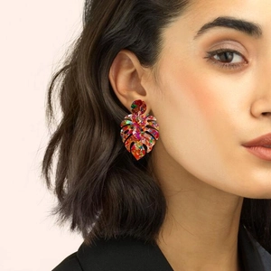 Chic multi-color glitter acrylic monstera leaf earrings worn by a model in a close-up view