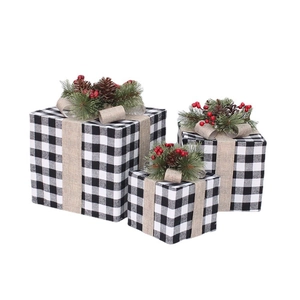 Trois boîtes cadeaux de Noël à carreaux avec pommes de pin et baies pour décoration