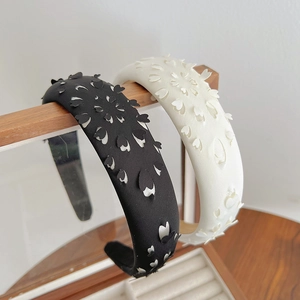 Detail showing white and black cut-out petal headbands on a wooden display stand
