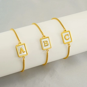 Detail of square shell bracelets with gold A, B, and C letters on display stand