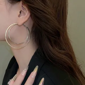 Boucles d'oreilles créoles doubles dorées pour femmes portées par un mannequin chic
