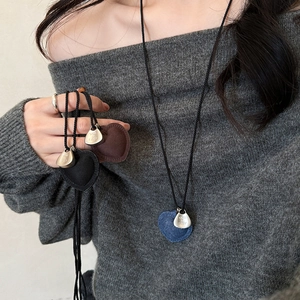 Detail showing heart-shaped fabric pendant necklaces in blue, brown, and black colors