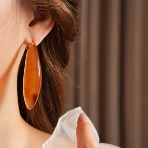 Gros plan de boucle d'oreille goutte en résine ambrée sur mannequin avec détails