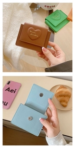 Detail showing brown and light blue heart embossed faux leather small wallets on a table