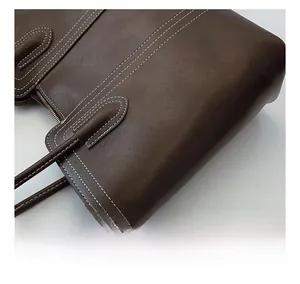 Detail of dark brown leather tote showing white contrast stitching and metallic zipper