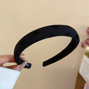 Close-up of thick black fabric headband with bow textures and woven label detail