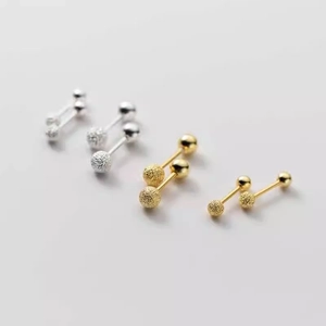Macro shot of silver and gold threaded ball earrings with matte and polished texture