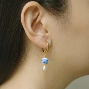 Detailed view of chinoiserie blue and white porcelain earrings with water drop pearl on model