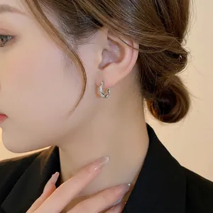 Silver twisted zircon hoop earrings with premium plating shown on a model's ear