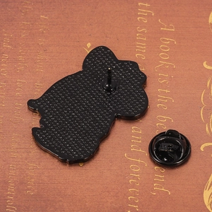 Black metal enamel cat pin back and butterfly clasp on vintage book background