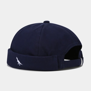 Detailed view of the navy blue dock worker cap featuring a small white dinosaur embroidery