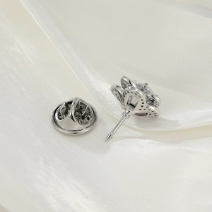 Macro shot of silver metal bow brooch with a sparkling gemstone on white silk background