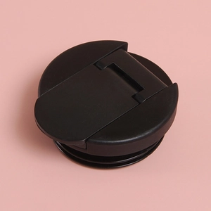 Detail of a black plastic tumbler lid with foldable handle on a pink background