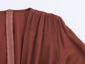 Detailed view of the shoulder pleats and invisible zipper on the brick red V-neck dress