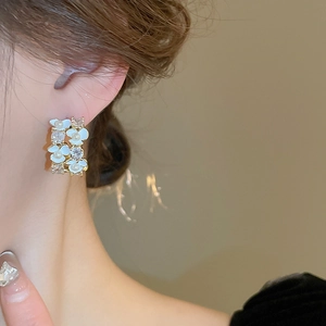 Close-up of golden floral earrings with white pearls and sparkling zircons on a model