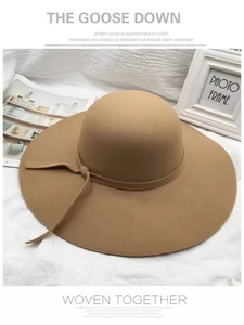Detailed view of camel wool felt wide-brim hat with matching ribbon on white fabric