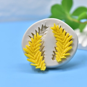 White silicone leaf mold for soap and fondant with two yellow leaf-shaped finished products