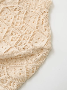 Detailed macro view of beige knit cardigan showing complex diamond crochet pattern