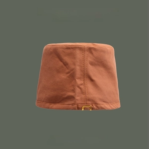 Close-up of caramel cotton bucket hat featuring fine texture and metal logo buckle