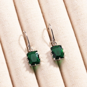 Gros plan de boucles d'oreilles rectangulaires en zircon vert avec finition argentée