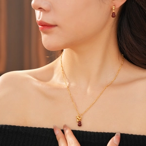 Detailed close-up of a model wearing the 18k gold-plated red gourd necklace and earrings set