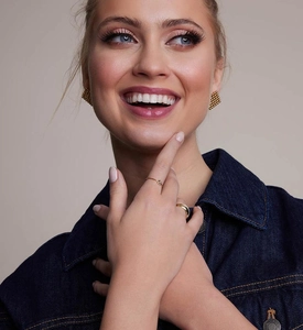 Close-up of minimalist gold earrings and stacked rings worn by a female model