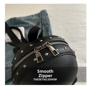 Detail of smooth metal double zippers and silver studs on the black round skull backpack