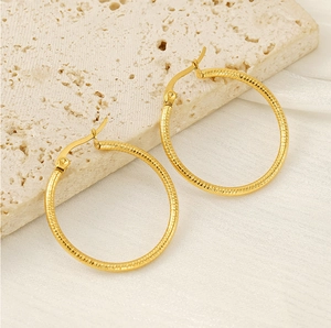 Detailed macro view of 18k gold-plated stainless steel hoop earrings with spiral texture