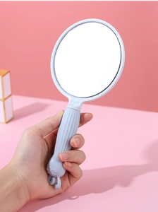 Close-up of light blue handheld makeup mirror with textured handle and cartoon decor