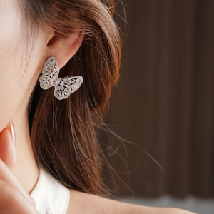 Detailed close-up of butterfly stud earrings with micro-set zircons on a model