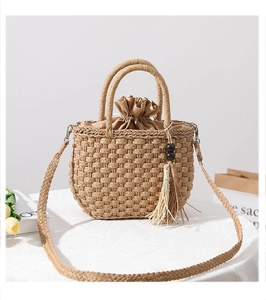 Detail of straw woven handbag featuring wooden bead tassels and drawstring fabric liner