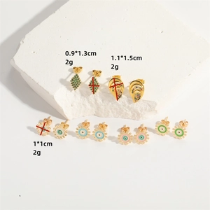 Golden gear and evil eye stud earrings with cubic zirconia inlay on white stone pedestal