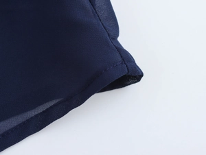 Detail of dark blue chiffon sleeveless shirt showing hem stitching and fabric texture