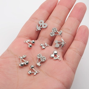 Polished silver cherry charms for jewelry making held in palm for size scale