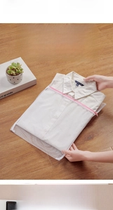 Detailed view of a white mesh laundry bag with pink zipper protecting a collared shirt