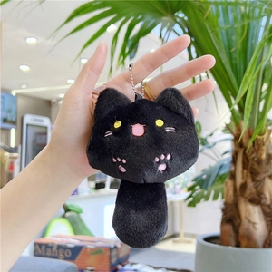 Close-up of black plush cat keychain with yellow eyes and pink paw embroidery detail