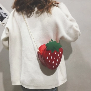 Detail of creative strawberry-shaped crossbody bag with red patent leather and gold chain