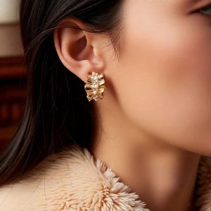 Detail of 14k gold plated C-shaped earrings with pearls and ruffled metal on model