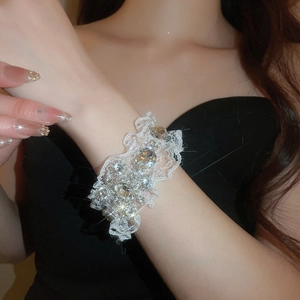 Gros plan du bracelet en dentelle blanche orné de strass étincelants au poignet