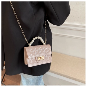 Detail of pink jelly bag with quilted texture, pearl handle, and gold chain strap
