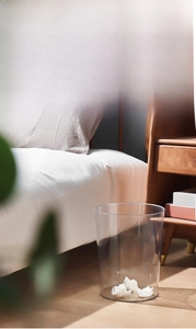 Detail view of large transparent PET waste bin used in a bedroom setting