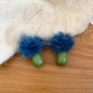 Dettaglio di orecchini a gancio in oro con pompon blu e perline verdi a goccia