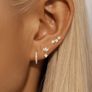 Close-up of gold petal earrings and sparkling cubic zirconia studs set on a female ear